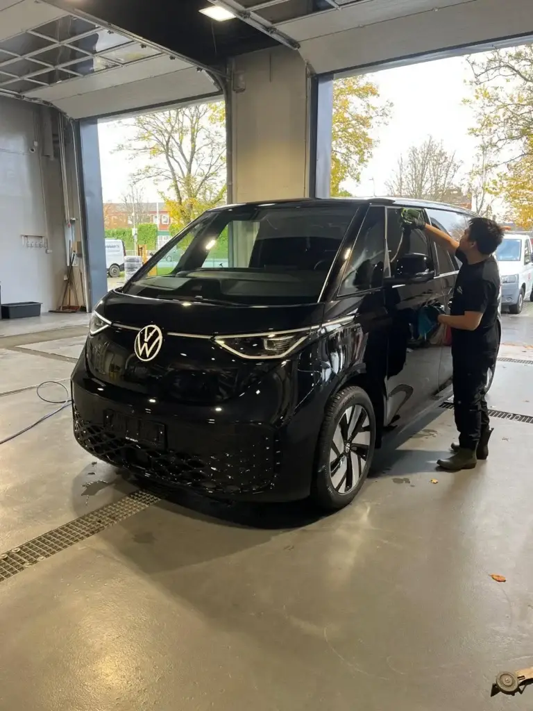 Medarbejder tørrer en VW ID. Buzz af efter vask
